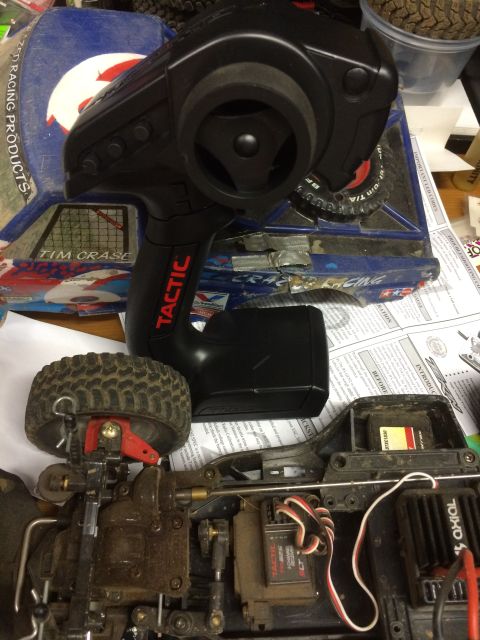 1989 Ford Bronco - A close-up view shows the remote control for an RC car, with the car's chassis, suspension, and electronics visible below. The remote has a…