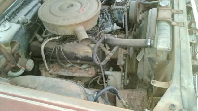 Engine bay of a classic car, showing the engine, radiator, fan, and air cleaner.