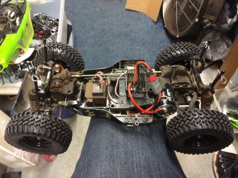 1989 Ford Bronco - A top-down view of a dirty remote-controlled rock crawler chassis with large tires, suspension components, and electronic parts visible. Th…