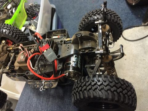 1989 Ford Bronco - The underside of a modified remote-control car chassis is shown, featuring a brushless motor, electronic speed controller, and suspension c…
