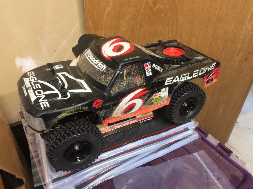 Black remote-controlled monster truck with red "6" decals and dirt