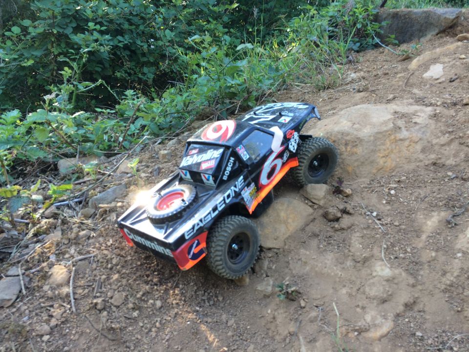 Remote-controlled rock crawler truck with 'Valvoline' and 'Bosch' decals on a rocky trail.
