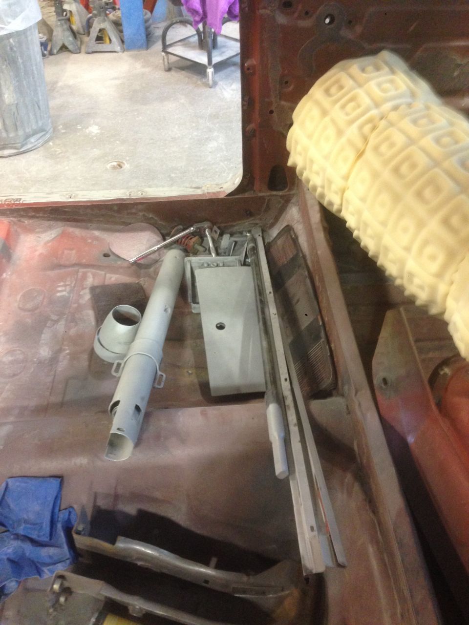 Interior of a vintage Ford Fairlane with disassembled parts and yellow foam padding.