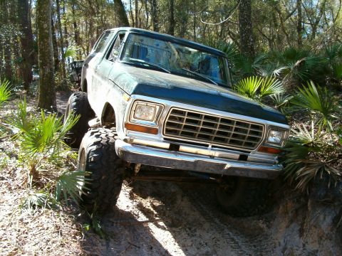 1991 Ford Bronco - This dark green Ford Bronco, likely from 1978, navigates a challenging off-road trail.