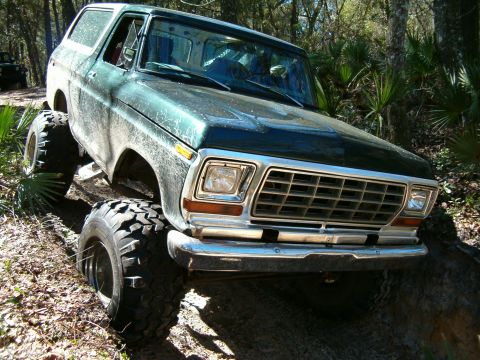 1991 Ford Bronco - Modified Ford Bronco navigating an off-road trail with large tires and lifted suspension.