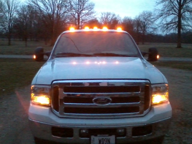 White Ford F-250 pickup truck with illuminated amber cab lights and headlights.