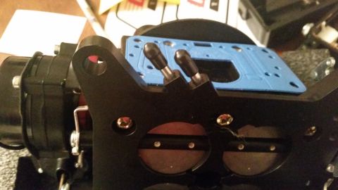 1981 Ford Bronco - A close-up view shows the top of a black carburetor with a blue gasket and two black vacuum pods. The carburetor's throttle plates are visi…