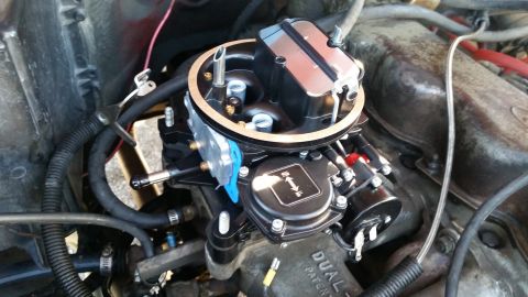 1981 Ford Bronco - A close-up view of a newly installed black carburetor on a V8 engine, with various hoses and wiring connected.