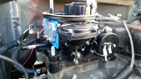 1981 Ford Bronco - A close-up view of a newly installed carburetor on a V8 engine. The carburetor is black and silver with a blue gasket visible.