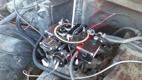 1981 Ford Bronco - A close-up view of a newly installed aftermarket carburetor on a V8 engine. The carburetor is black and red, with various hoses and wiring…