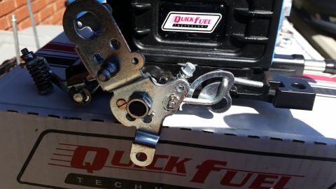 1981 Ford Bronco - A close-up, angled shot shows the linkage and spring mechanism of a Quick Fuel carburetor, resting on the product box.