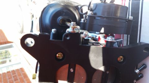 1981 Ford Bronco - A close-up view of a black automotive part, likely a carburetor or throttle body, with visible screws and linkages. The part is mounted on…