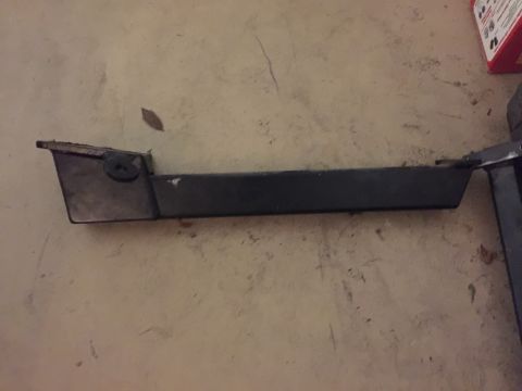 1965 Ford Mustang - A black plastic trim piece is shown lying on a concrete floor. The trim piece has a rectangular shape with a slight angle at one end and a…
