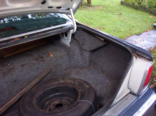 1991 Ford Crown Victoria LTD - The interior of a car's trunk is shown, revealing a spare tire and a wooden plank.