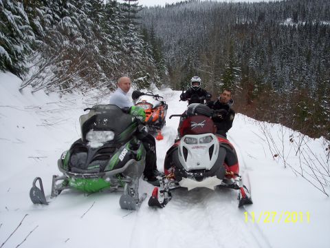 2004 Arctic Cat King Cat 900 - Two snowmobiles are parked on a snow-covered trail, likely during a winter excursion in a wooded area.