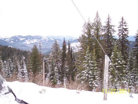 2004 Arctic Cat King Cat 900 - A snowmobile sits in a winter landscape, surrounded by snow-covered trees and distant hills.