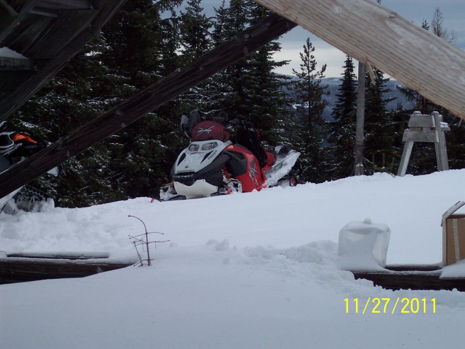 Red and white snowmobile partially buried in snow, front view