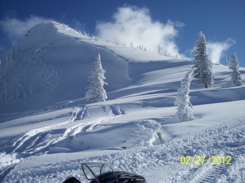 2004 Arctic Cat King Cat 900 - Snowmobile parked on a snowy slope with a mountain in the background.