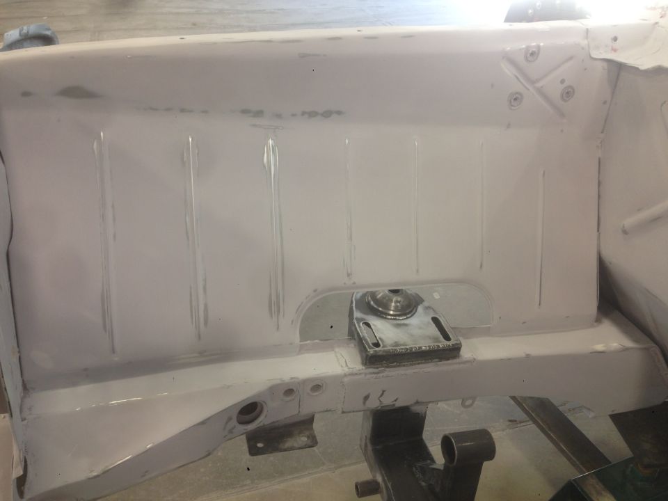 Interior of a classic car with pink primer, showing a mounted metal bracket.