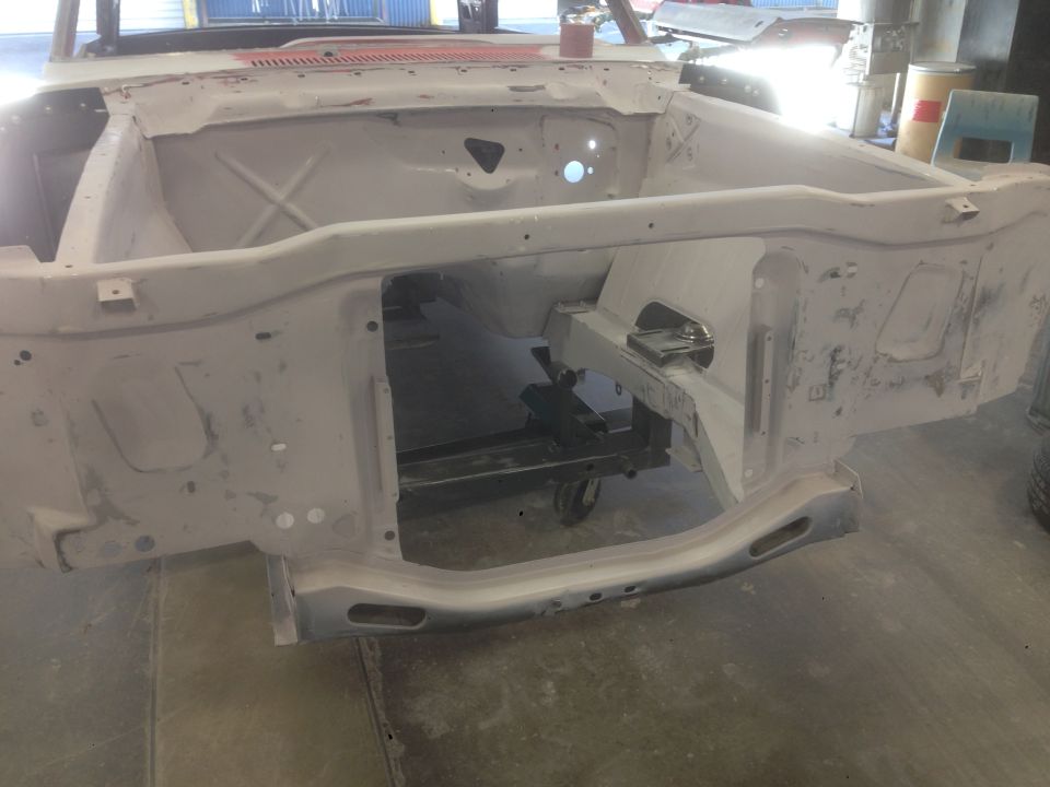 1964 Ford Fairlane body in primer, front view, in a workshop.