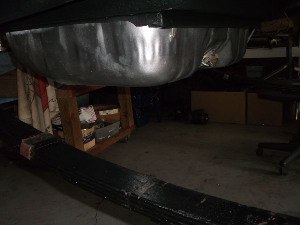 Underside of a vehicle showing a fuel tank and leaf spring assembly.