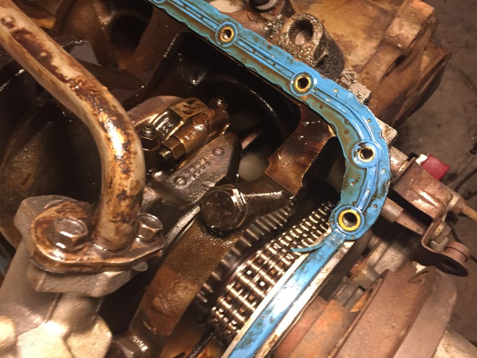Engine internal components: timing chain, blue gasket, oil pan, bolts.
