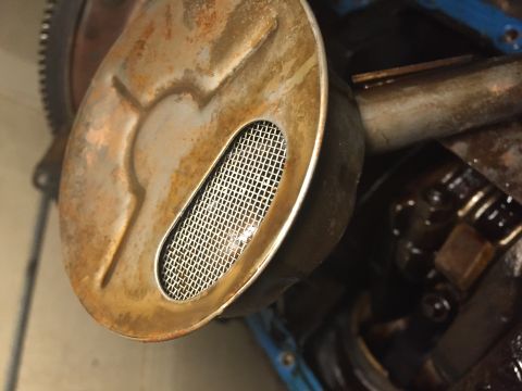 1989 Ford Bronco - This is a close-up view of an engine's oil pump screen, showing its mesh filter and surrounding metal components.