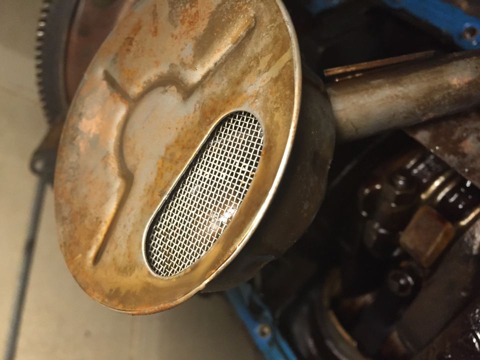 Close-up of an engine's oil pump screen with rust and mesh