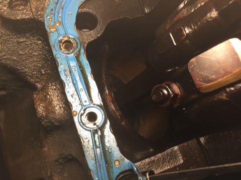 1989 Ford Bronco - Detail of an engine gasket and a bolt, likely from a vehicle's internal engine components.
