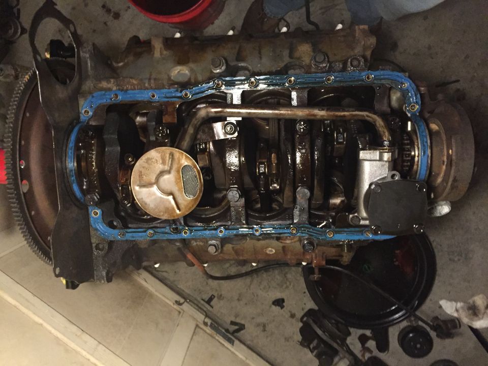 Engine with oil pan removed, showing crankshaft and oil pickup screen. Supermotors.net logo visible