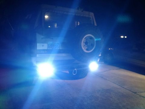 1992 Ford Bronco - The rear of a Ford Bronco is illuminated by bright off-road lights at night.