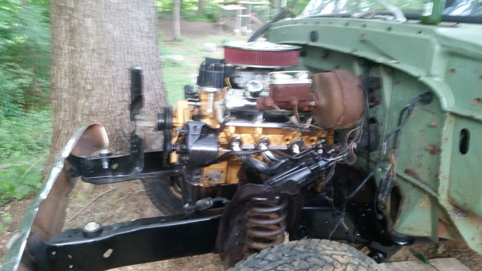 Engine bay of a green truck, showing the V8 engine, brake booster, and part of the frame