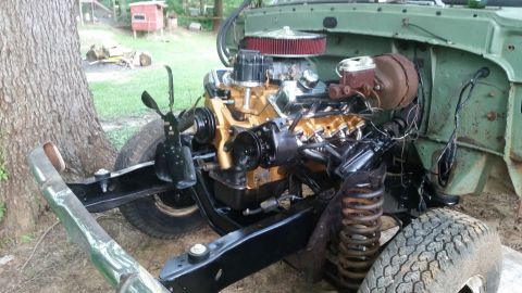 Engine and chassis of a green vehicle, with gold-colored engine components and black frame. Tires and suspensi