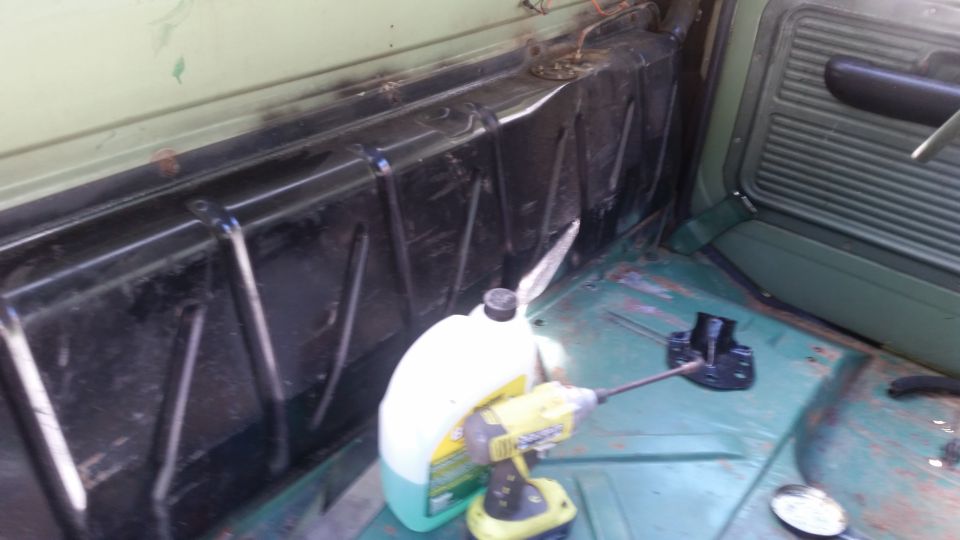 Interior view of a vehicle's cargo area with a fuel tank and a drill
