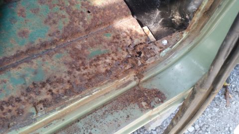 rusted out floor pan of a vehicle, showing significant corrosion and damage