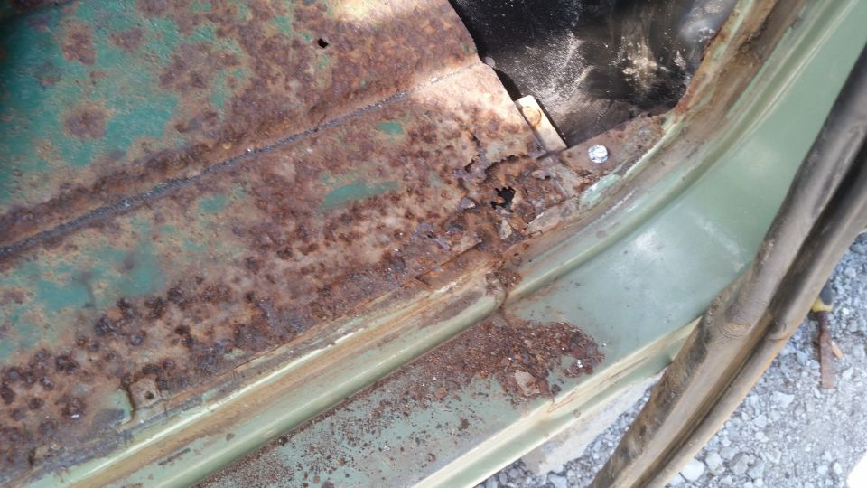 rusted out floor pan of a vehicle, showing significant corrosion and damage