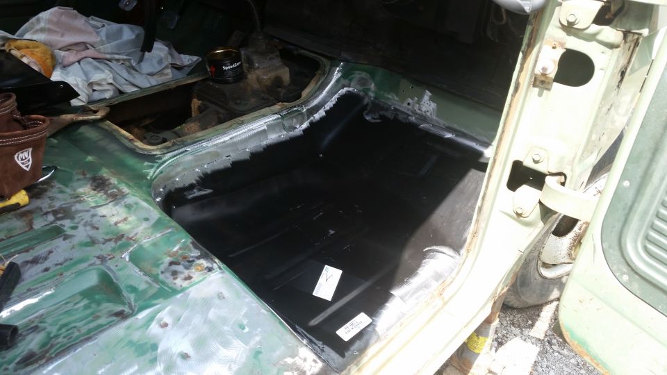 1978 Ford Bronco interior showing green painted floor with black undercoating, rust repair, and a brown tool bag