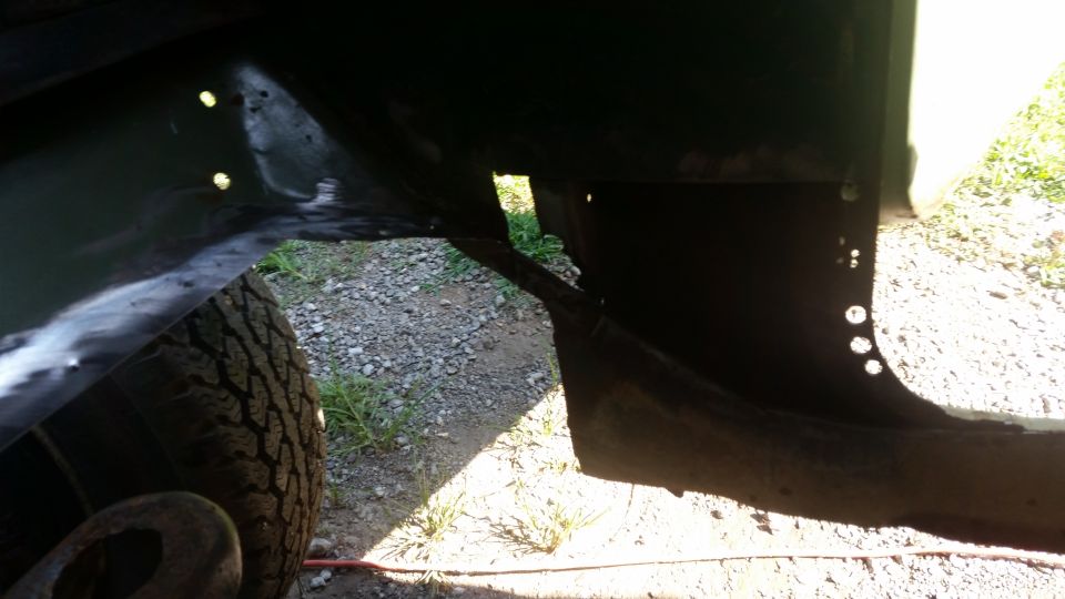 Close-up of vehicle frame structure near a tire, showing metalwork and holes