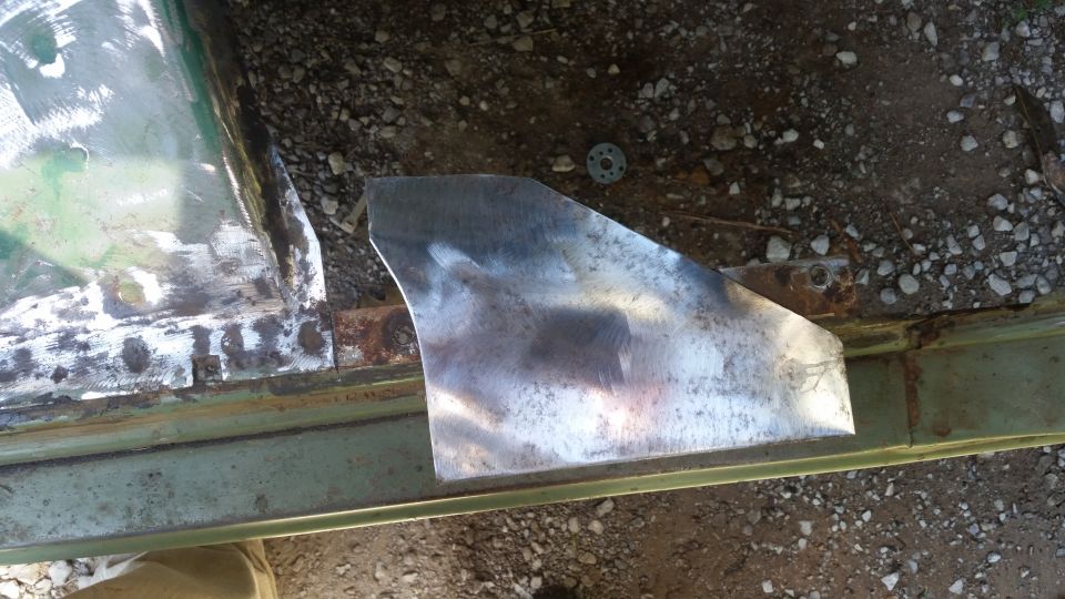 Metal patch welded onto a green vehicle's rusty door frame