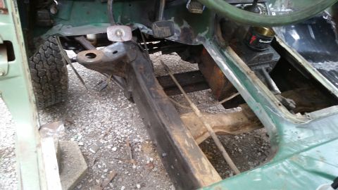 Green vehicle frame and floor pan with tire visible. Steering wheel and pedals are present