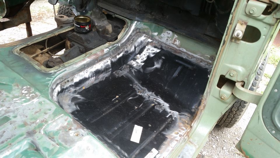 Green vehicle interior floor with exposed metal and black coating, showing rust repair
