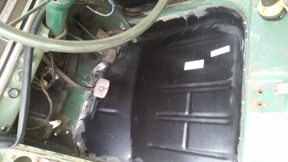 Interior floor of a vehicle, showing the driver's side pedals and a black floor pan