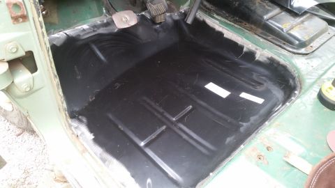 Green vehicle interior floor pan with black coating and visible metal bracing