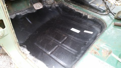 Interior floor of a vehicle, looks like it's being prepped for something. Black coating on the metal
