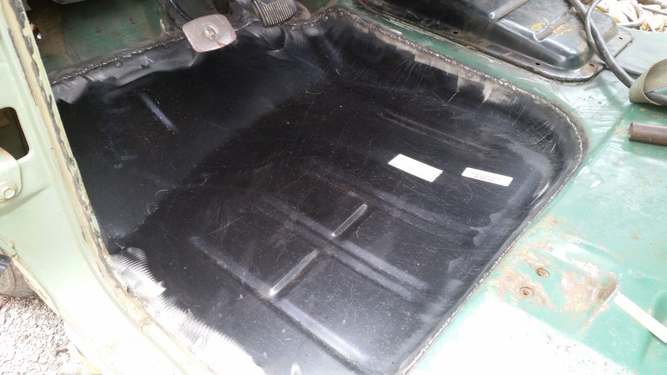 Interior floor of a vehicle, looks like it's being prepped for something. Black coating on the metal
