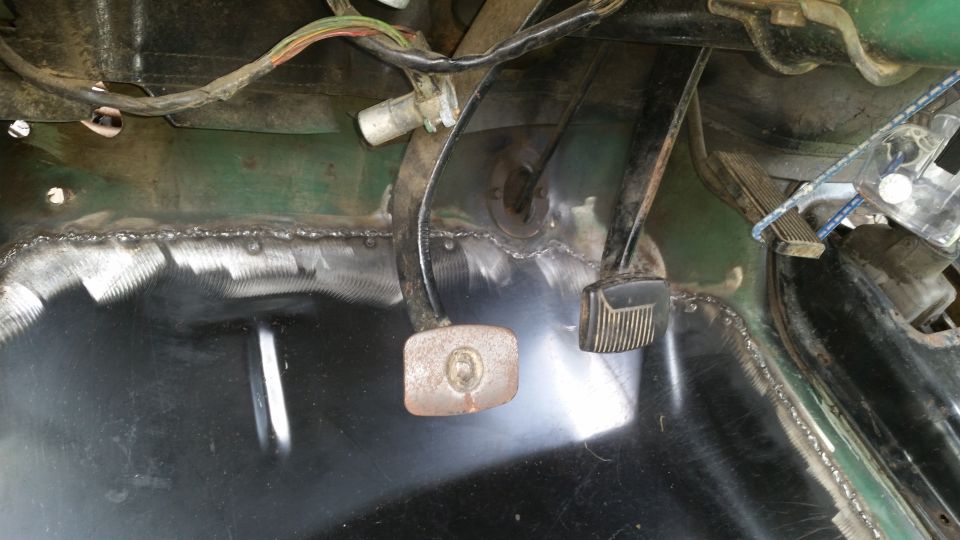 Vehicle interior floor with brake and clutch pedals, showing welded metal repairs