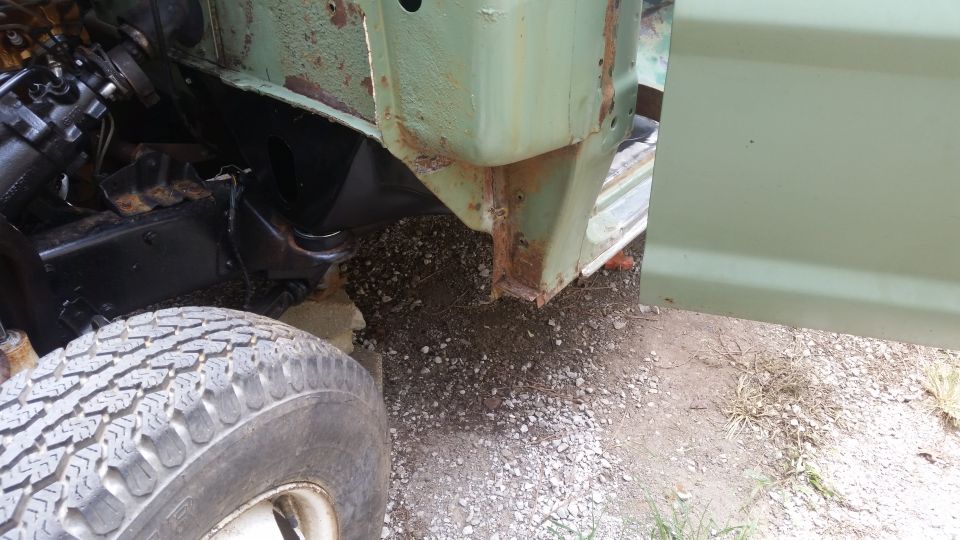 Light green vehicle fender and tire with visible rust and engine components