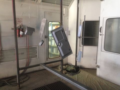 1964 Ford Fairlane - Various car parts are suspended and awaiting a fresh coat of paint inside a spray booth.