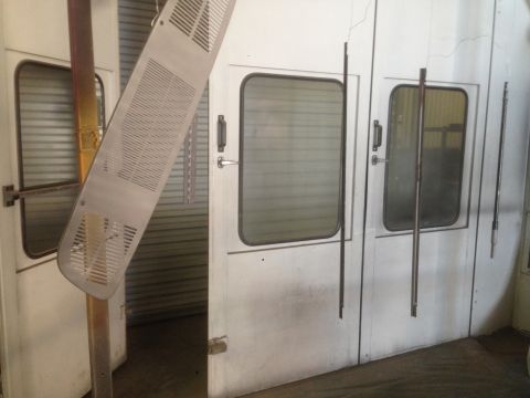 1964 Ford Fairlane - A perforated metal car grille part is shown hanging in front of a spray booth.