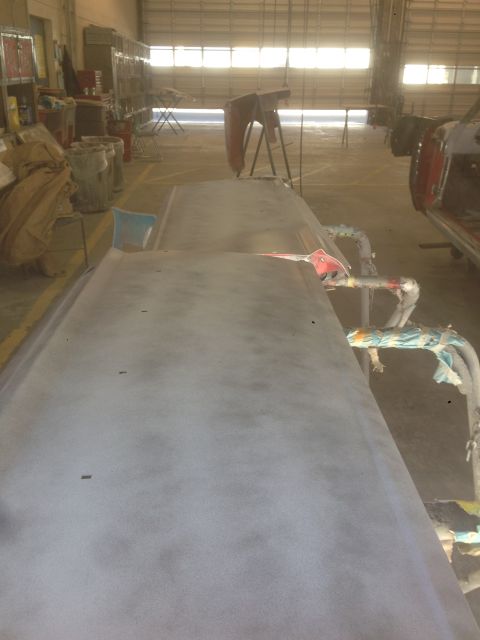 1964 Ford Fairlane - A car body, prepped for paint, sits in a workshop bay with a large garage door in the background.